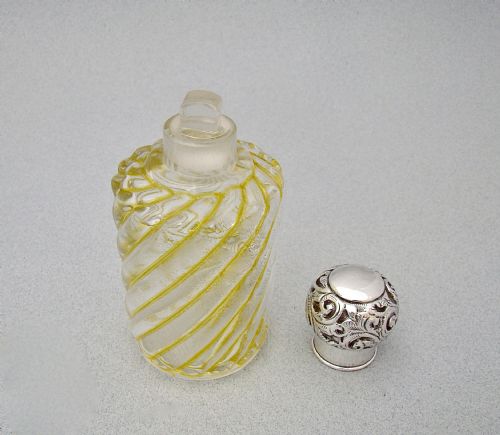 fig 2. A clear glass cologne bottle featuring diagonal yellow swirl patterns, topped with a chased sterling silver stopper.