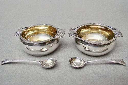 fig 2. A cased pair of Edwardian sterling silver open salt cellars with stylised handles and matching spoons set in a purple velvet fitted presentation box.