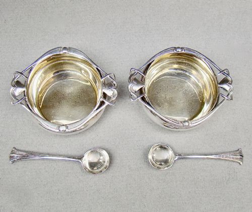 fig 3. A cased pair of Edwardian sterling silver open salt cellars with stylised handles and matching spoons set in a purple velvet fitted presentation box.