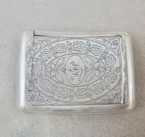 fig 1. A rectangular Georgian sterling silver snuff box featuring hand-engraved oak leaf motifs, a central monogram cartouche, and a curved profile.