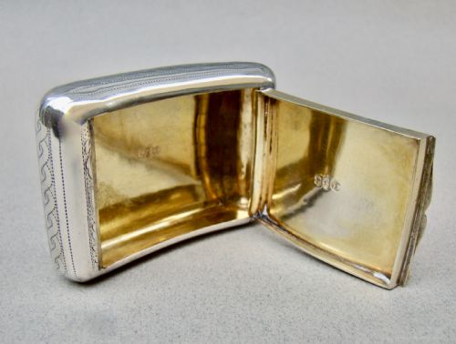 fig 4. A rectangular Georgian sterling silver snuff box featuring hand-engraved oak leaf motifs, a central monogram cartouche, and a curved profile.