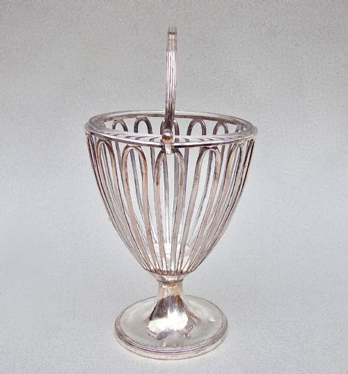 fig 1. A Georgian Old Sheffield Plate wirework sugar vase featuring an arched swing handle, loop-pattern wire body, and a turned pedestal base.