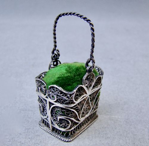 fig 1. A Georgian silver filigree basket pin cushion with a twisted wire handle and a green velvet cushion pad.