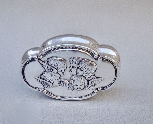 fig 1. An Edwardian sterling silver lobed trinket box with a hinged lid embossed with five cherub heads surrounded by a beaded border.