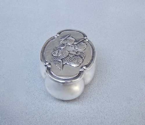 fig 2. An Edwardian sterling silver lobed trinket box with a hinged lid embossed with five cherub heads surrounded by a beaded border.