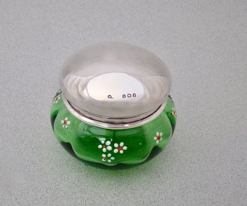 fig 1. A small green glass jar decorated with white enamel flowers and topped with a hallmarked sterling silver cap.