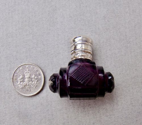 fig 1. A miniature barrel-shaped purple amethyst cut glass scent bottle with a silver cap and collar.