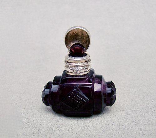 fig 2. A miniature barrel-shaped purple amethyst cut glass scent bottle with a silver cap and collar.