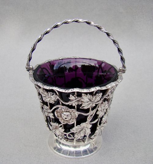 fig 1. A sterling silver wirework sugar basket featuring a twisted swing handle, cast vine leaf motifs, and a removable purple glass liner.