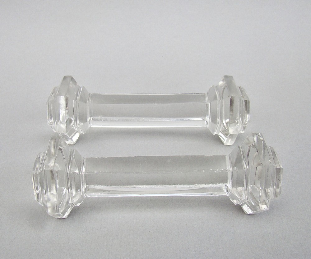 A pair of clear Victorian cut crystal glass knife rests featuring faceted octagonal ends and a central connecting bar.