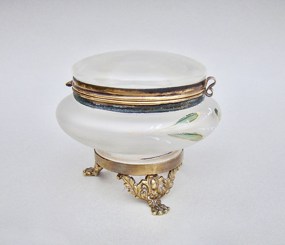 A rounded frosted glass trinket box featuring painted green leaf motifs, a brass hinged rim, and four scroll-form brass feet. View VI