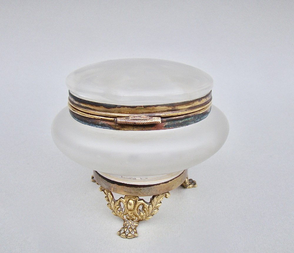 A rounded frosted glass trinket box featuring painted green leaf motifs, a brass hinged rim, and four scroll-form brass feet. View VII