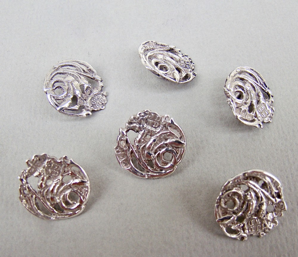 A cased set of six Art Nouveau pierced sterling silver buttons arranged inside a red velvet-lined fitted box. View III