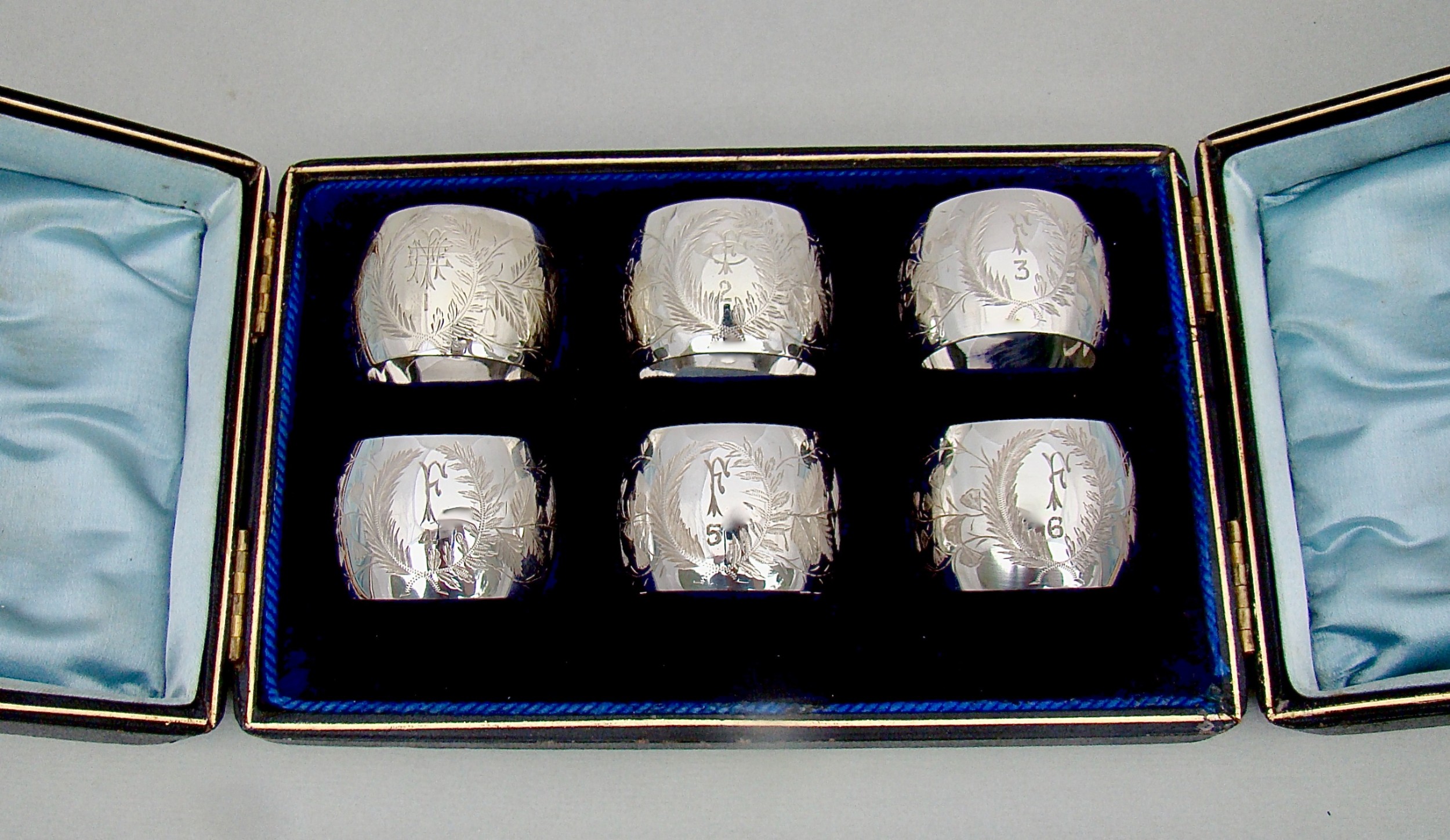 EXQUISITE CASED SET OF SIX VICTORIAN SILVER PLATED NUMBERED AND INITIALLED NAPKIN RINGS, CIRCA 1890
