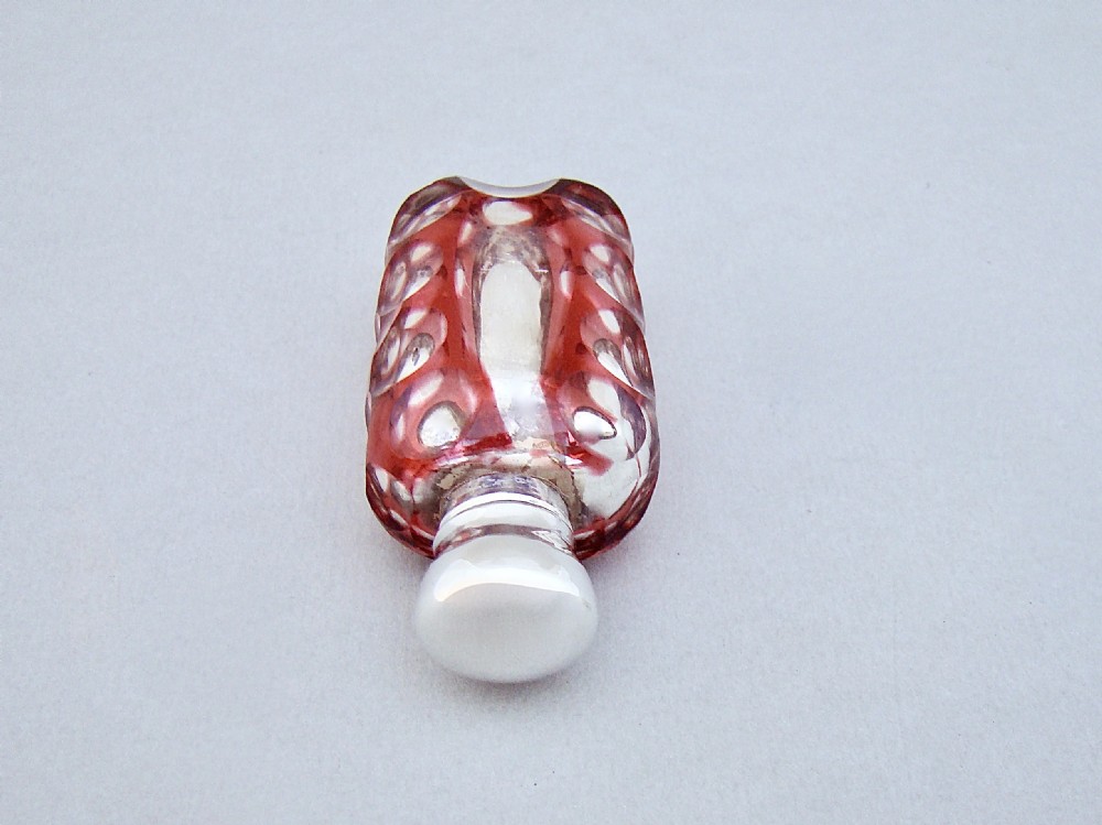 A Victorian scent bottle featuring a silver cap and a red and silvered mercury glass body with cut geometric patterns. View VI