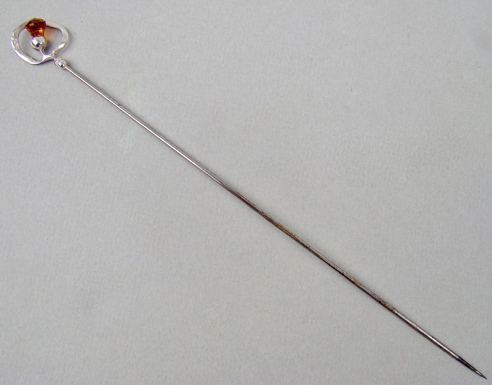 An antique silver hat pin featuring a Scottish thistle design set with an amber glass top, stamped with C.H maker marks. View II