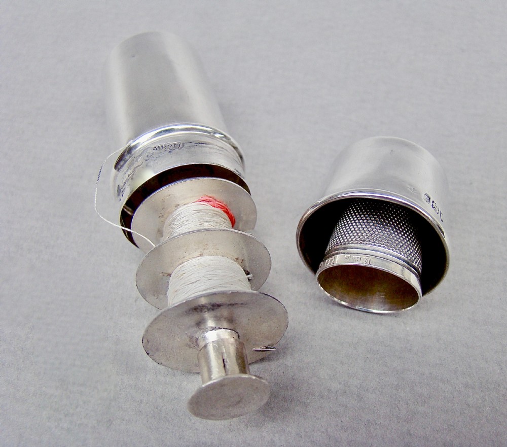 A disassembled 1913 sterling silver sewing compendium showing the cylindrical case, tiered thread spool holder, cap lid, and textured thimble. View VI