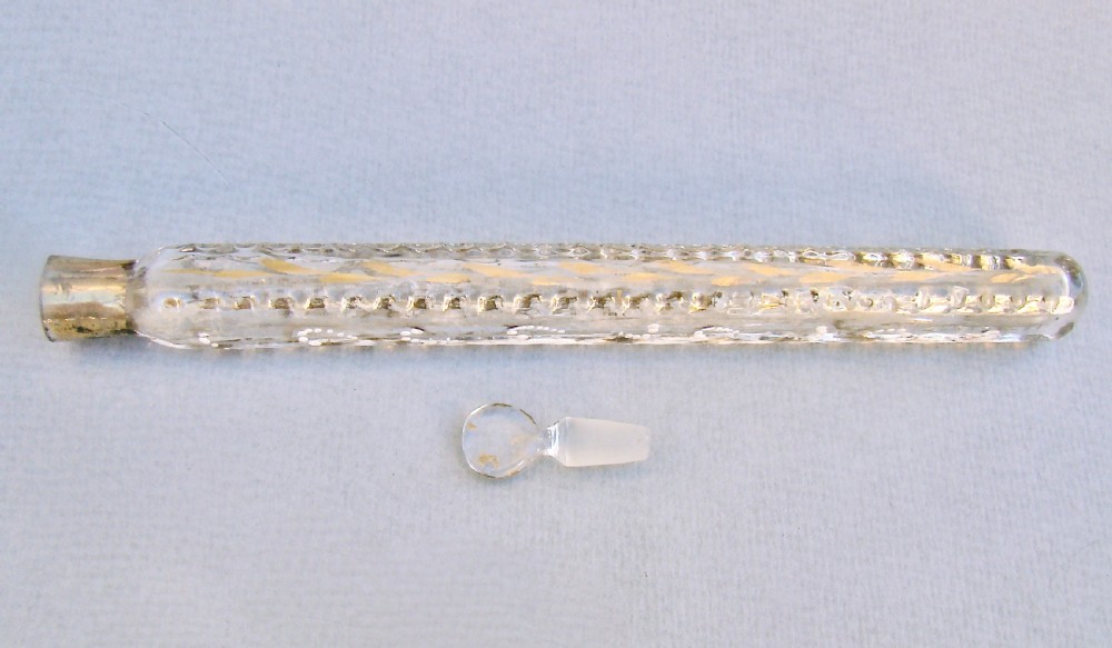 An elongated clear glass Oxford lavender scent bottle with hand-painted gold leaf scrollwork, white enamel accents, and a glass stopper. View V