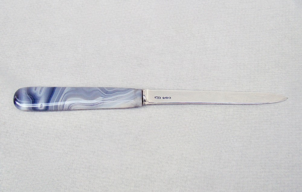 A Georgian sterling silver letter opener featuring a polished grey banded agate handle and hallmarked silver blade.