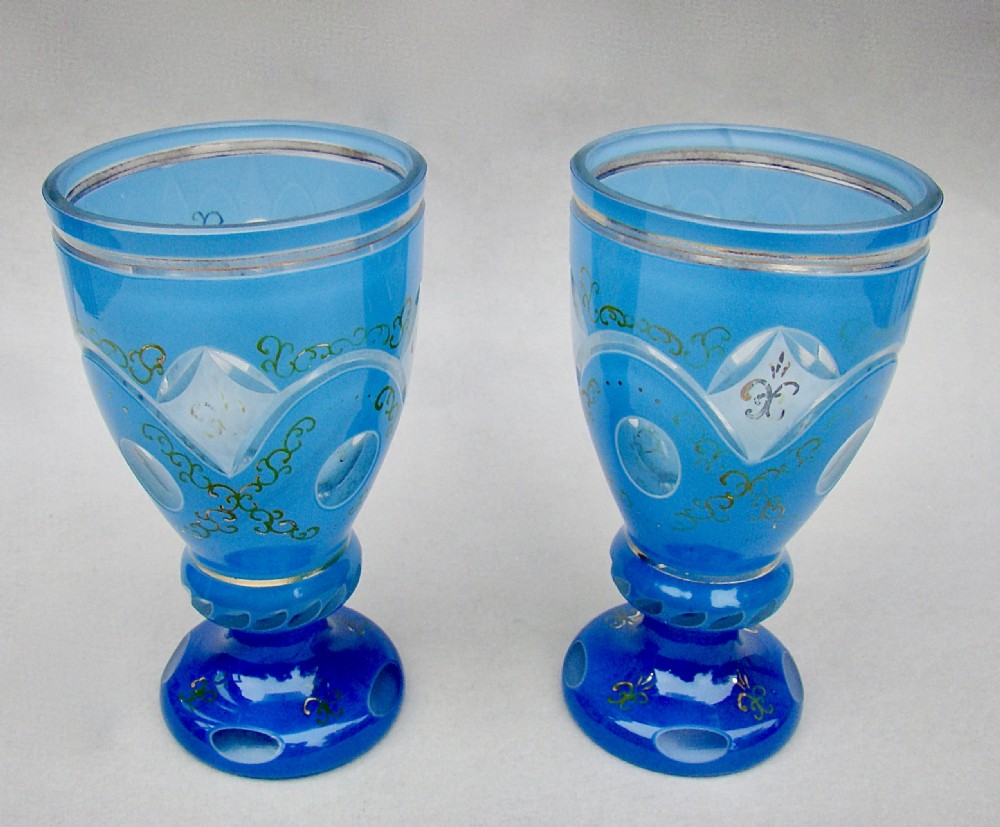 A pair of late nineteenth-century Bohemian blue cased glass goblets featuring cut-to-clear oval panels and gilt floral decoration. View VI