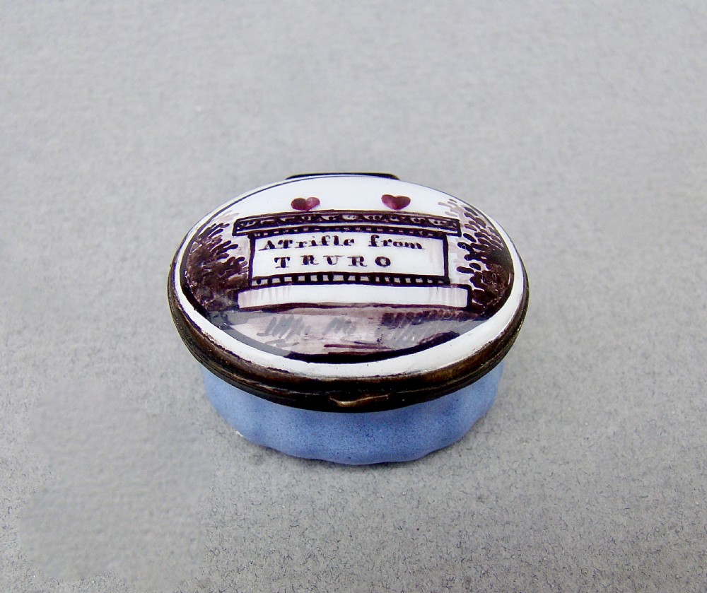 An oval Georgian enamel patch box featuring a light blue fluted base and a hinged white lid inscribed with A trifle from TRURO.