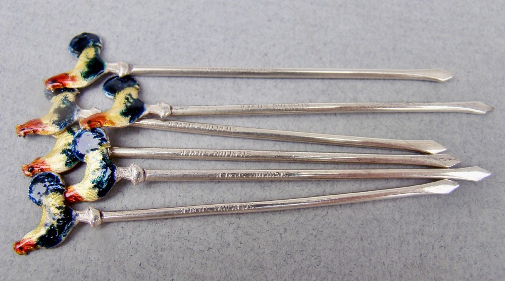 A cased set of six sterling silver cocktail sticks featuring colourful enamelled cockerel finials arranged inside a fitted cream-lined presentation box. View III