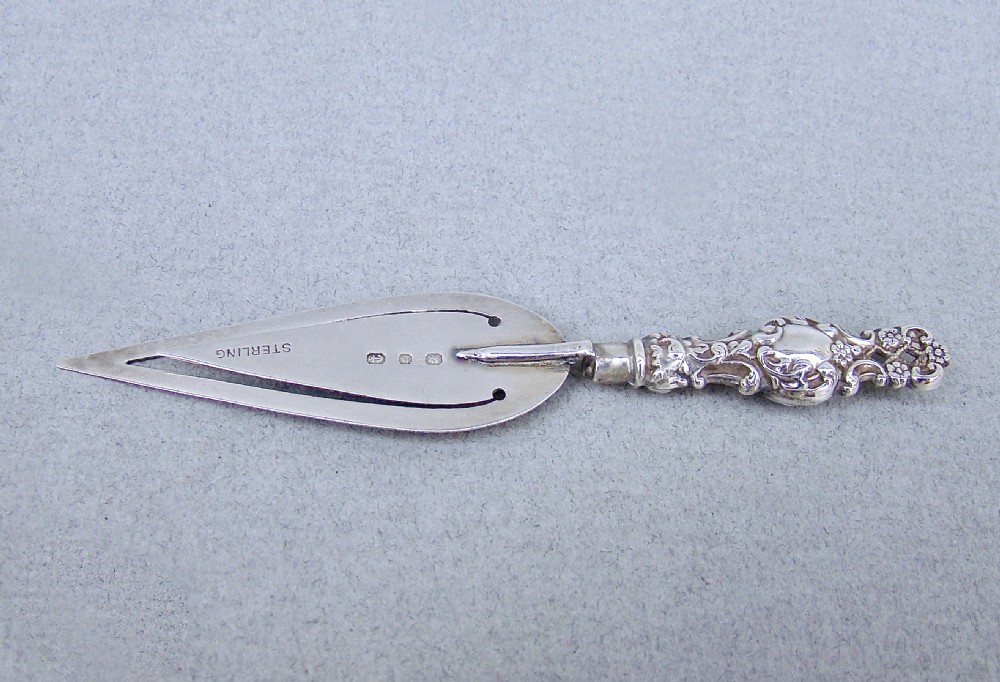 A Victorian sterling silver bookmark shaped like a small trowel with an ornate chased handle and English hallmarks stamped on the blade. View II
