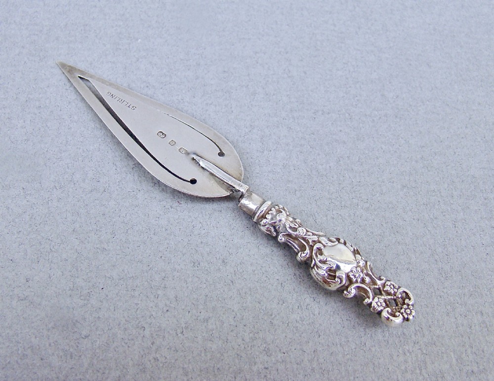 A Victorian sterling silver bookmark shaped like a small trowel with an ornate chased handle and English hallmarks stamped on the blade. View III
