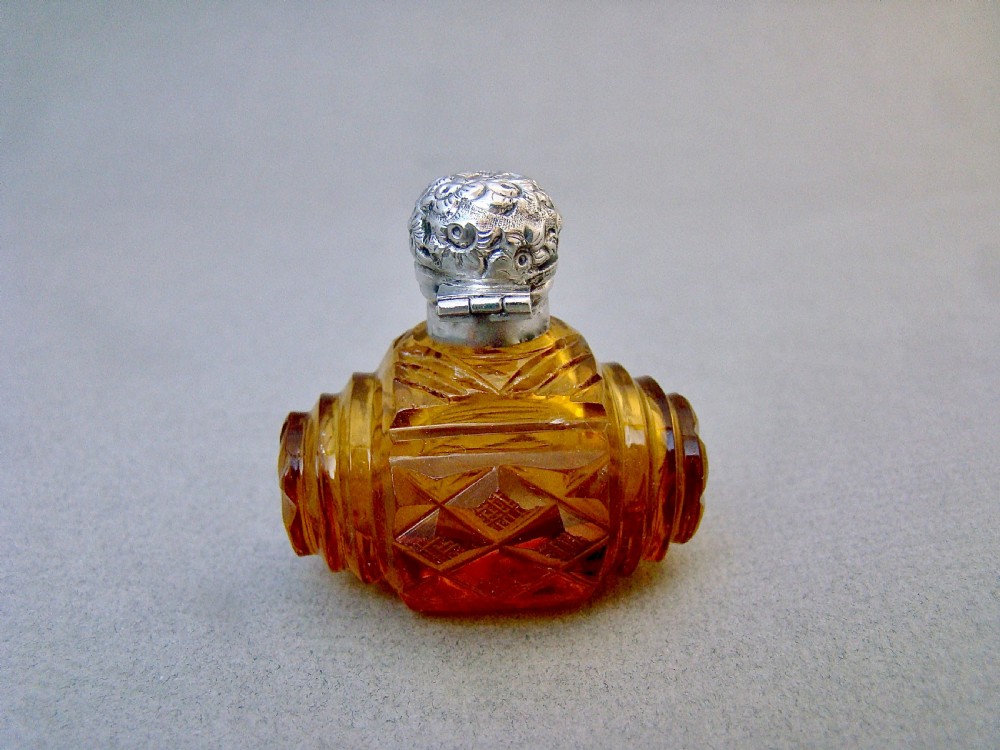 A late Victorian amber glass scent bottle featuring a faceted cut glass body and an embossed silver cap. View V