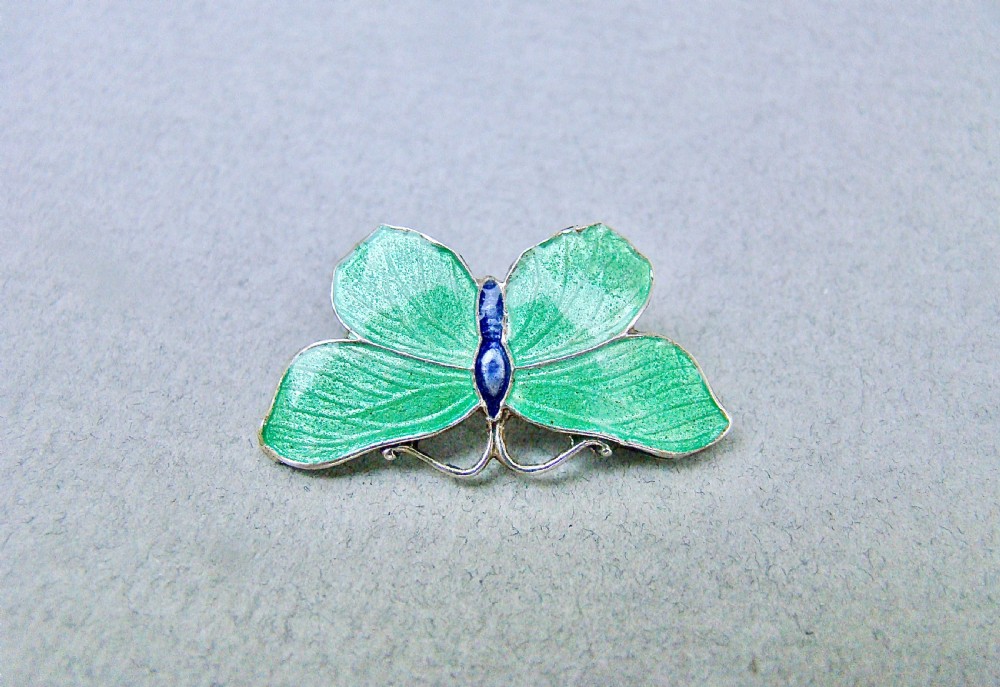 An Art Deco silver butterfly brooch featuring light green translucent enamel wings and a dark blue enamel body. View IV