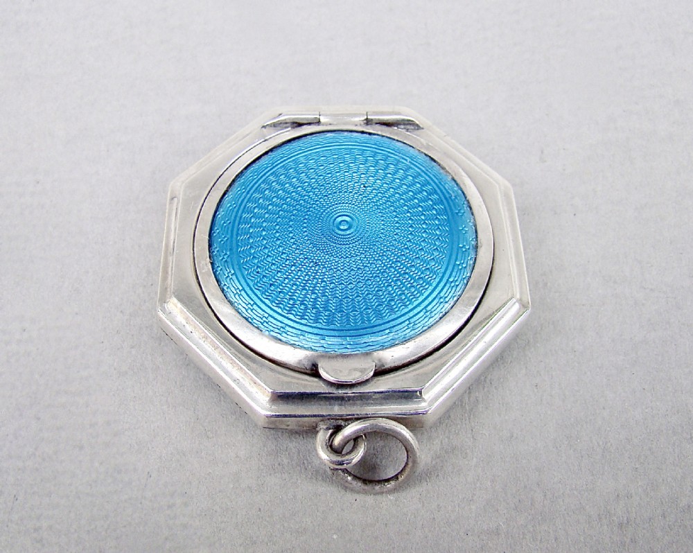 An octagonal sterling silver Art Deco compact featuring a central circular panel of bright turquoise blue guilloche enamel with a suspension loop.