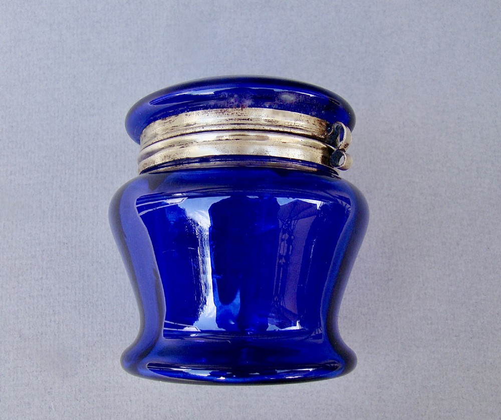 A deep cobalt blue glass dressing table jar featuring hand-painted white daisy enamel decoration and a hinged metal rim. View V