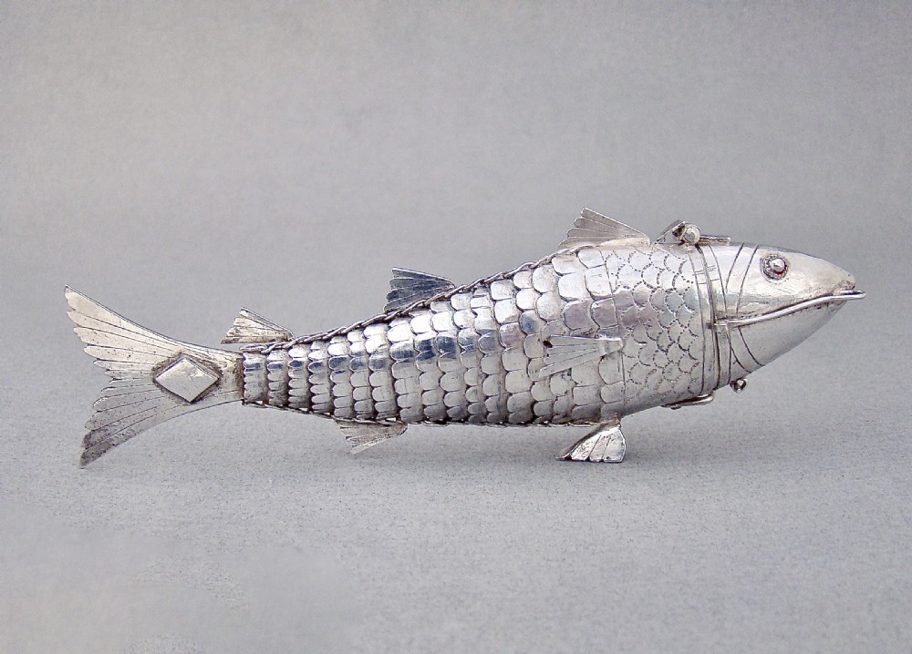 A Victorian sterling silver spice box sculpted in the detailed, flexible form of an articulated fish with stone eyes and engraved scales.
