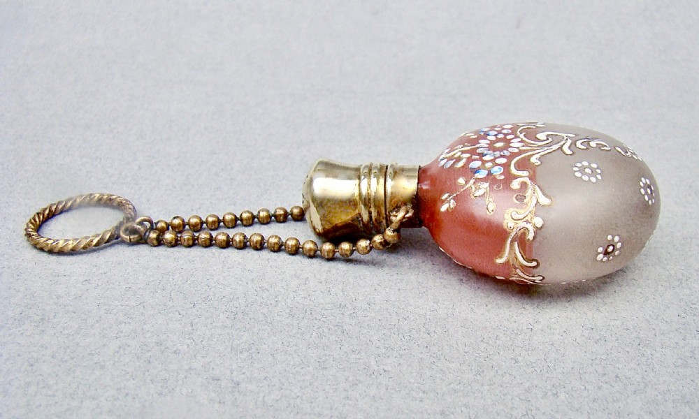 A nineteenth-century French satin glass chatelaine scent bottle decorated with hand-applied enamel scrolls and flowers, fitted with a gilded metal cap and chain. View IV