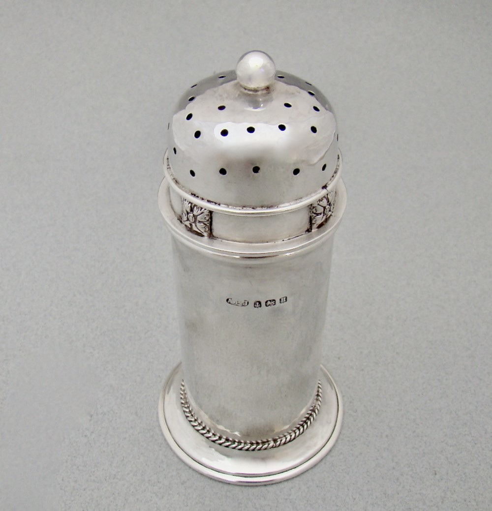 A cylindrical sterling silver sugar caster featuring a domed perforated lid, floral band motif, rope twist base, and visible English hallmarks.