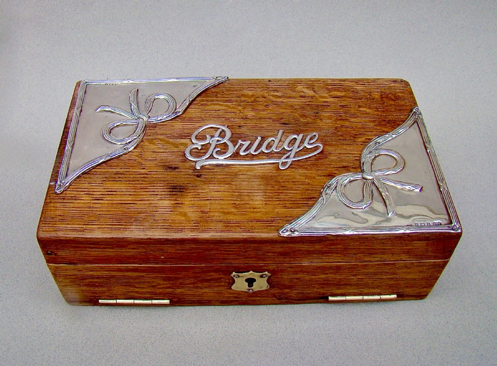 An Edwardian oak box featuring sterling silver ribbon corner mounts and a silver script word reading Bridge on the lid.