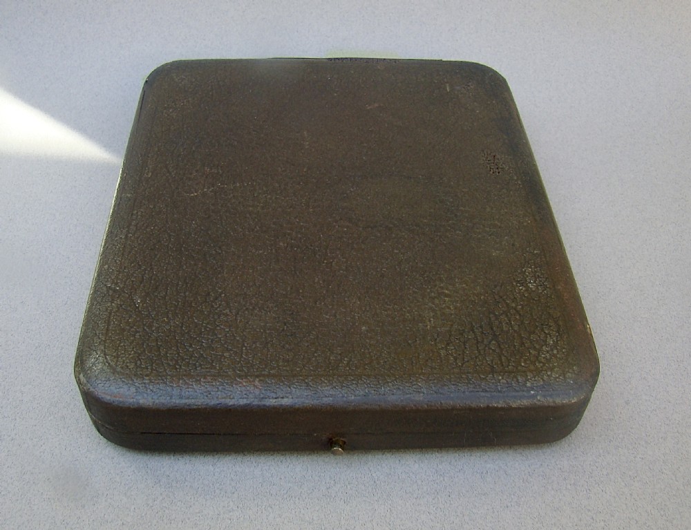 An Edwardian sterling silver card case designed in the shape of an envelope with a suspension chain, resting inside a velvet-lined fitted box. View VII