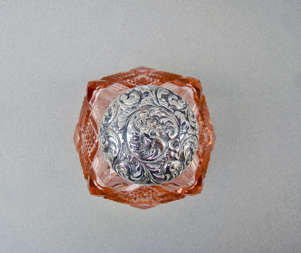 A Victorian pale salmon pink cut glass scent bottle featuring a hand-chased sterling silver top. View IV