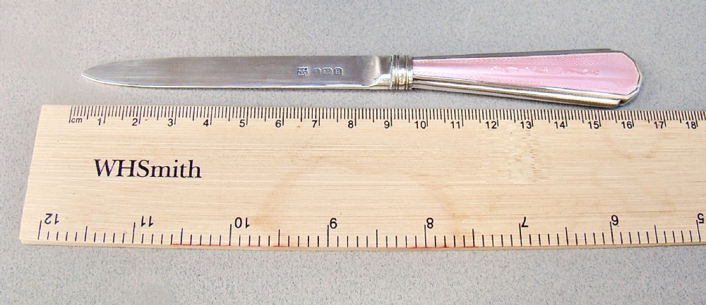 An Art Deco sterling silver letter opener featuring a tapered blade with English hallmarks and a pink guilloche enamel handle. View VI
