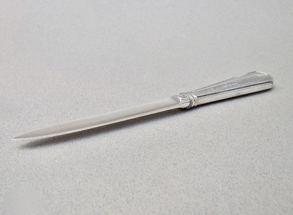 An Art Deco sterling silver letter opener featuring a tapered blade with English hallmarks and a pink guilloche enamel handle. View VII