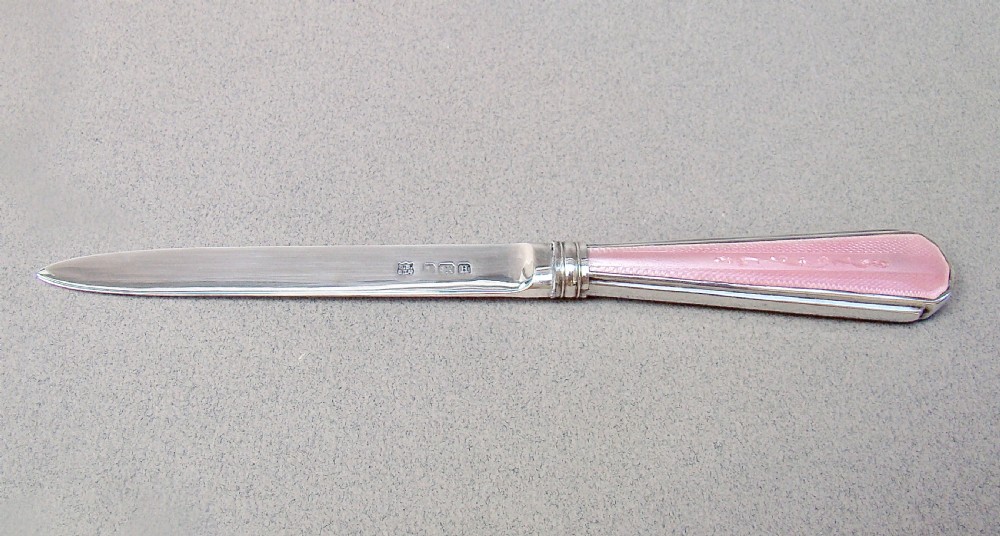 An Art Deco sterling silver letter opener featuring a tapered blade with English hallmarks and a pink guilloche enamel handle. View VIII
