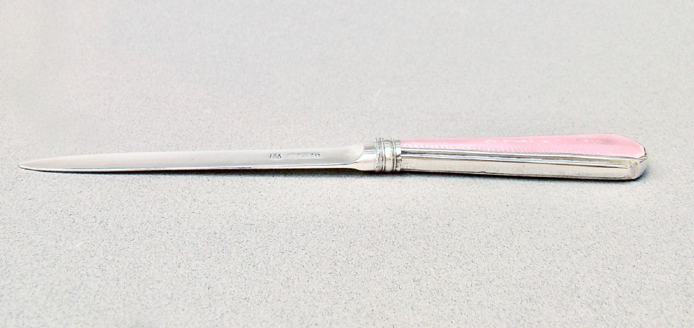An Art Deco sterling silver letter opener featuring a tapered blade with English hallmarks and a pink guilloche enamel handle. View IX