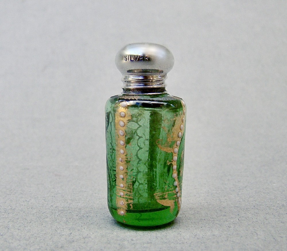 A miniature green glass scent bottle featuring painted gilt and enamel dot decoration, topped with a rounded silver screw cap stamped with SILVER.