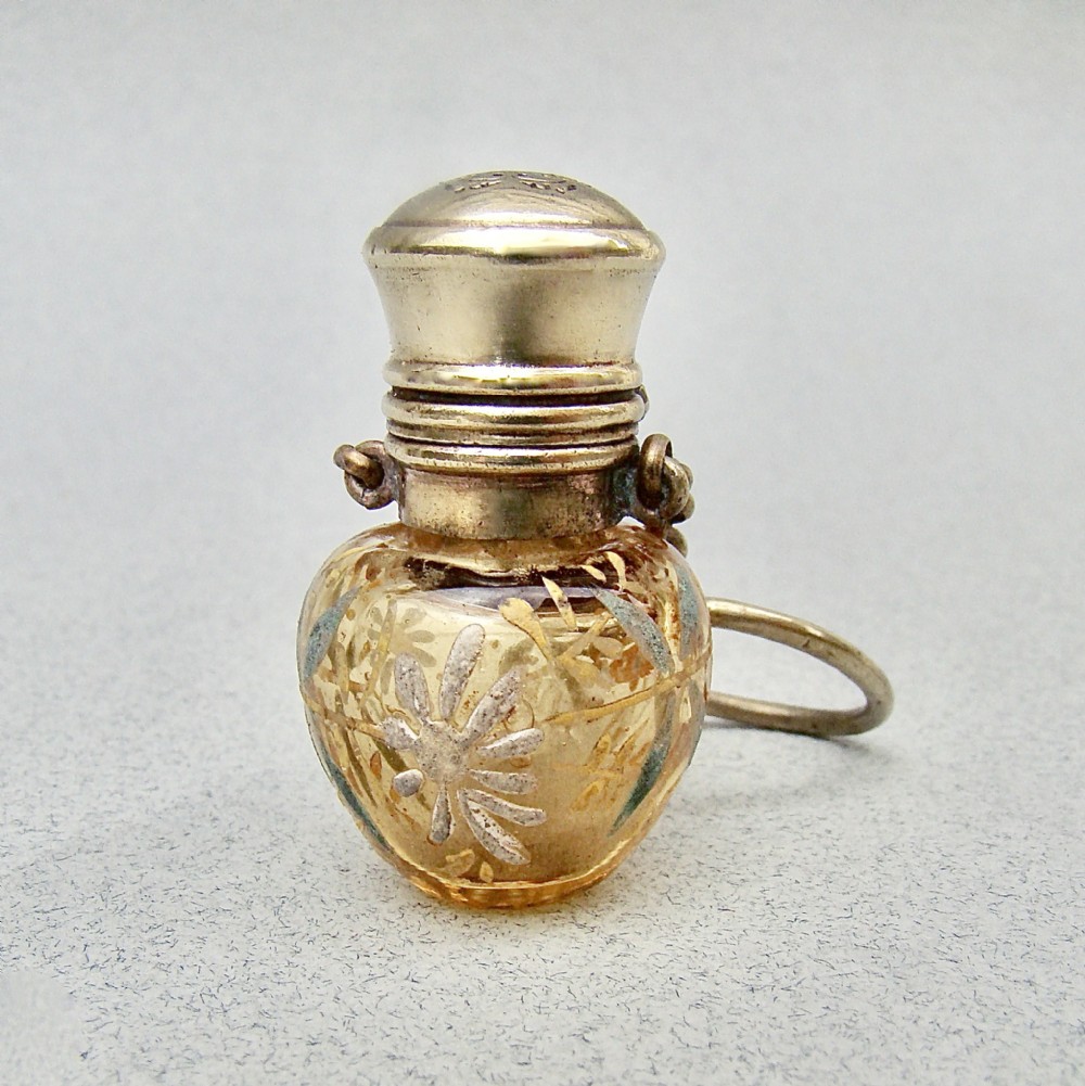 A late 19th-century amber glass chatelaine scent bottle decorated with gilded floral enamel details and a metal screw top with attachment rings.