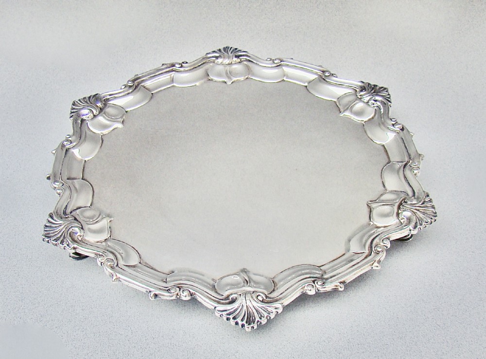 A circular late Victorian silver-plated salver featuring a moulded, scalloped rim decorated with shell motifs.