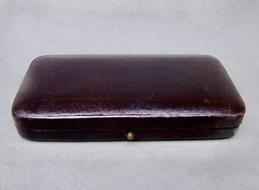 A cased set of two late Victorian sterling silver sardine servers featuring engraved scroll decorations resting inside an open fitted presentation box. View V