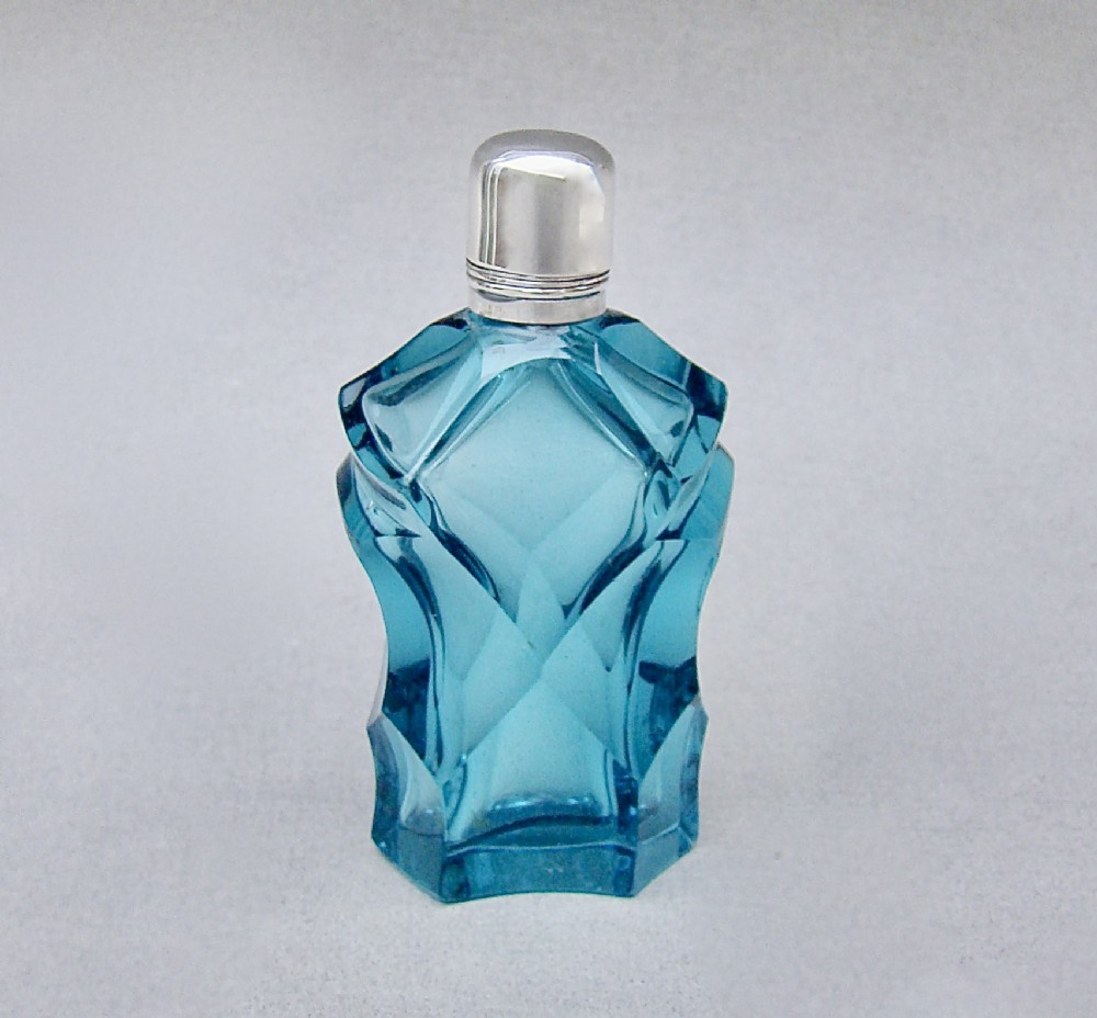 A Victorian sliced-cut teal glass scent bottle featuring geometric facets and a polished silver cap.