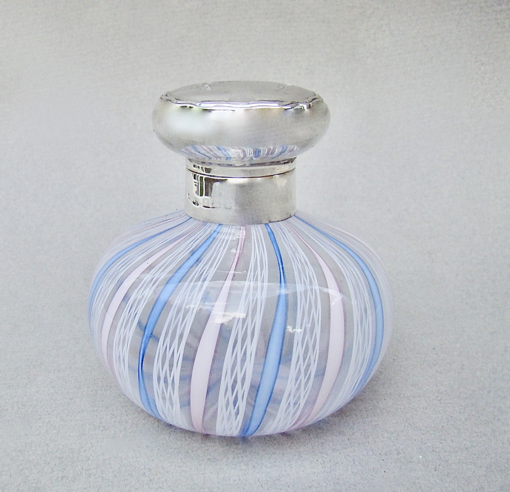 An Edwardian squat glass scent bottle featuring blue, white, and pink latticino stripes topped with a polished silver cap.