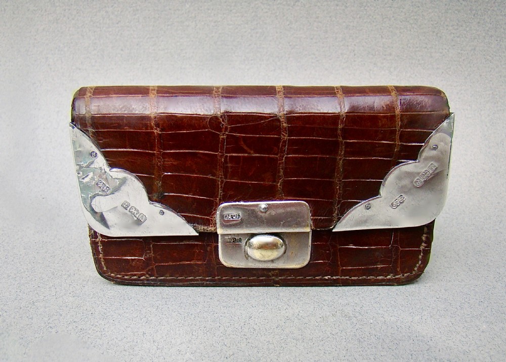 An Edwardian dark brown crocodile skin purse with silver corner mounts and a silver push-button clasp.