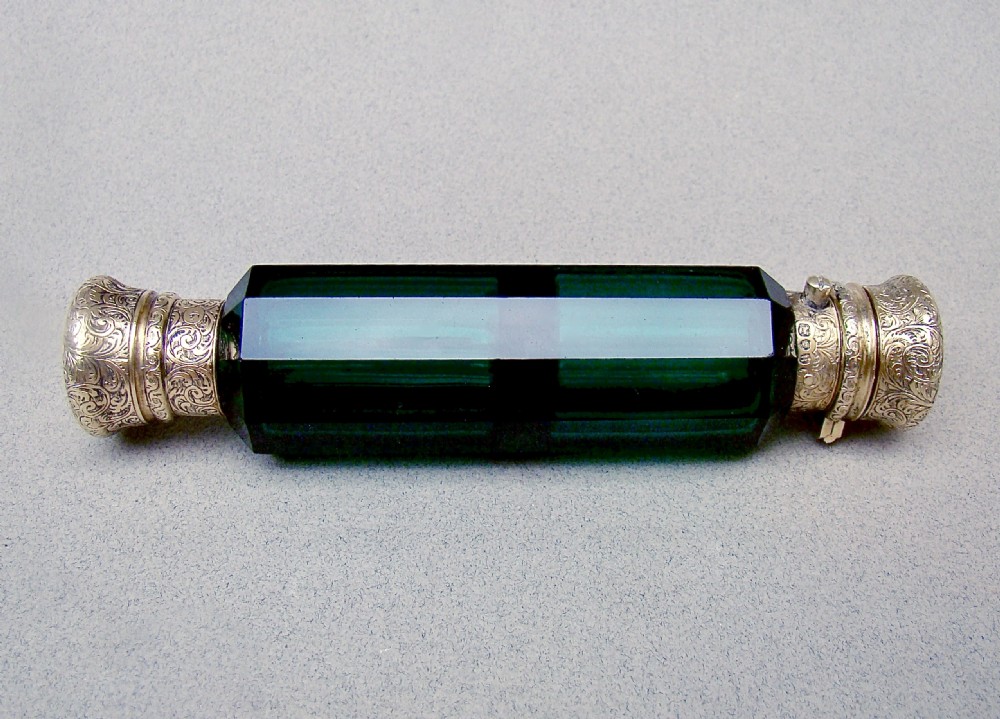 A Victorian double-ended faceted Bristol green glass scent bottle featuring intricately engraved silver-gilt caps on both ends. View II